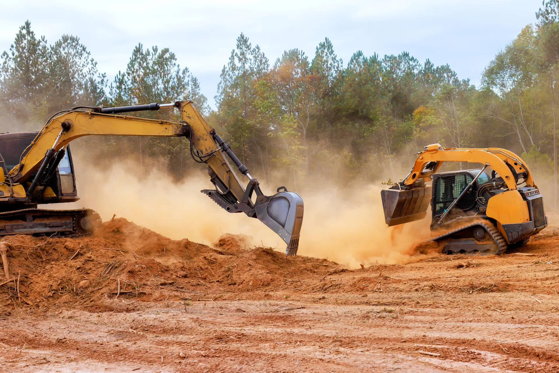 An excavator and front loader working on clearing land and moving earth
